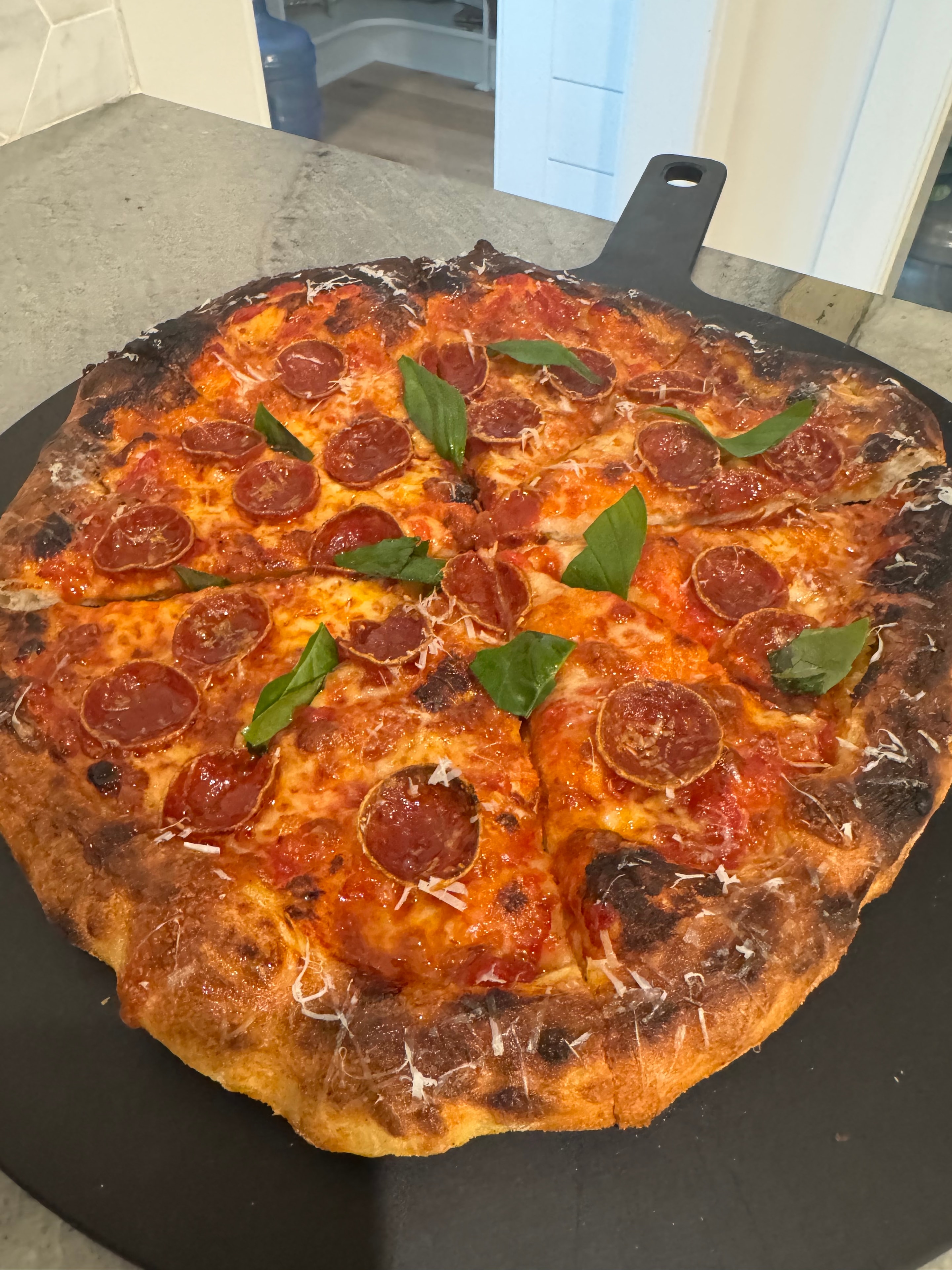 Greg's pepperoni pizza with fresh basil on peel
